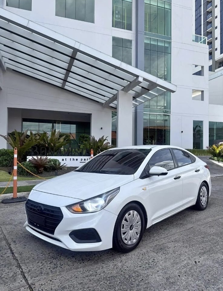 Hyundai Accent blanco de Transporte Moderno Panamá frente a una torre residencial